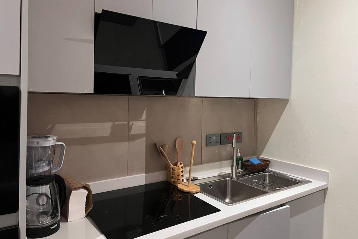 Una cocina moderna con estufa negra, pileta y encimera.