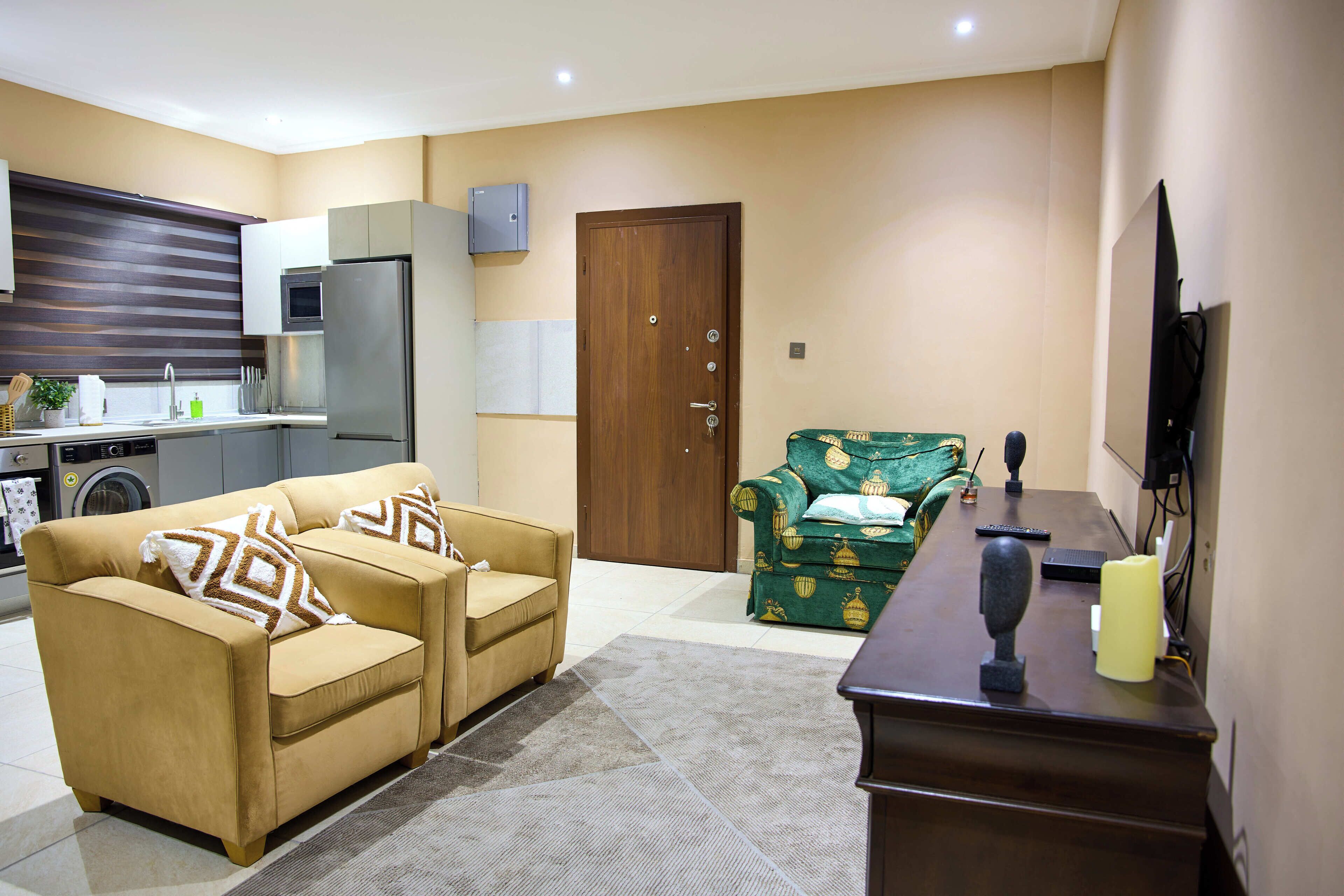 A living room with a sofa, a green armchair, a coffee table, and a TV.