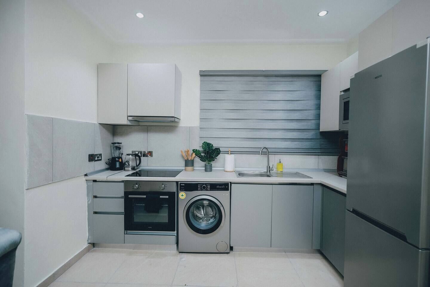 A compact kitchen with a dishwasher, oven, washing machine, and a refrigerator.