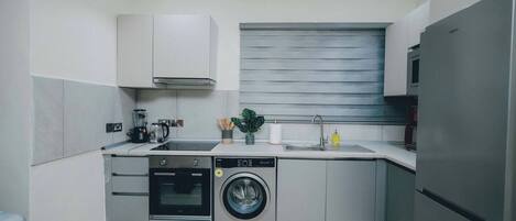 Cocina compacta con lavavajillas, horno, lavadora y refrigerador.