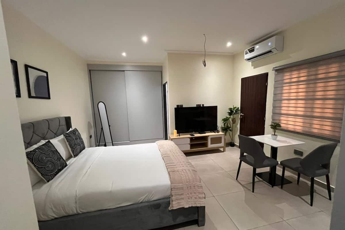 Un dormitorio moderno con cama, televisor, escritorio y una silla.