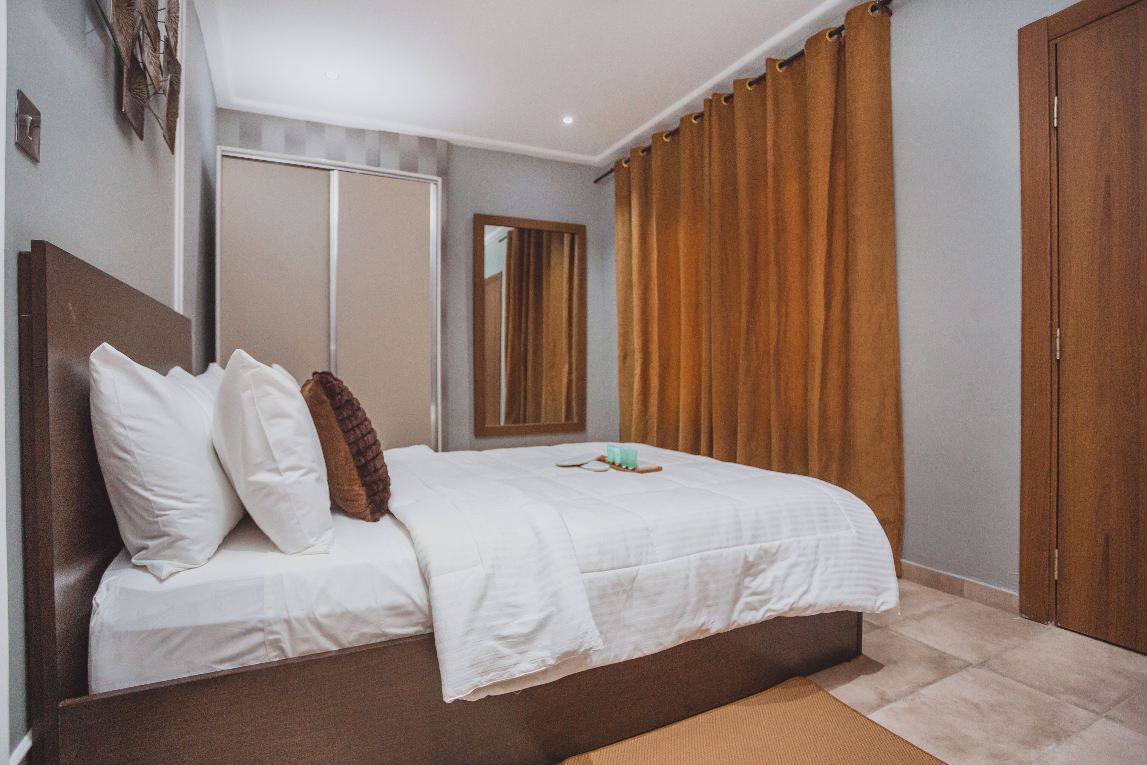 Un dormitorio con cama, espejo, armario y cortina.