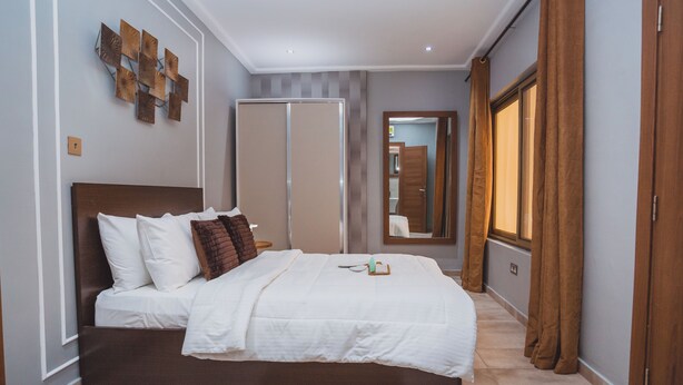 Un dormitorio con cama, mesita de noche, espejo y armario.