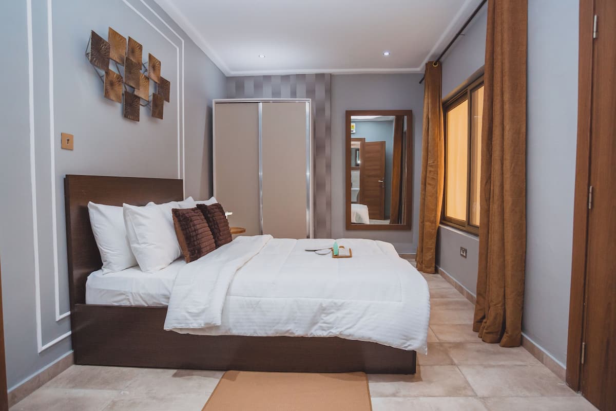 Un dormitorio con cama, mesita de noche, espejo y armario.