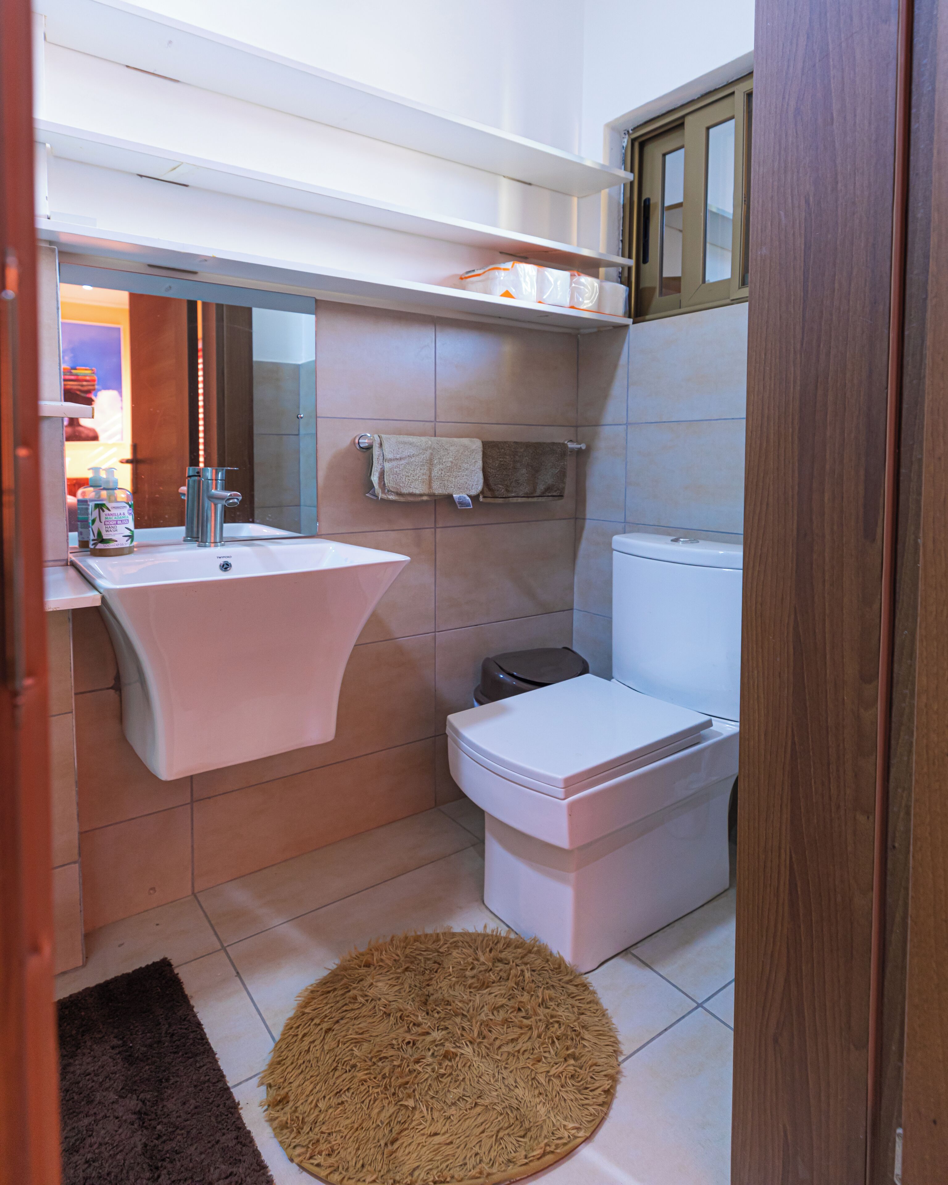 Ein Badezimmer mit Waschbecken, Spiegel, Handtuchhalter, Toilette und Teppichboden.