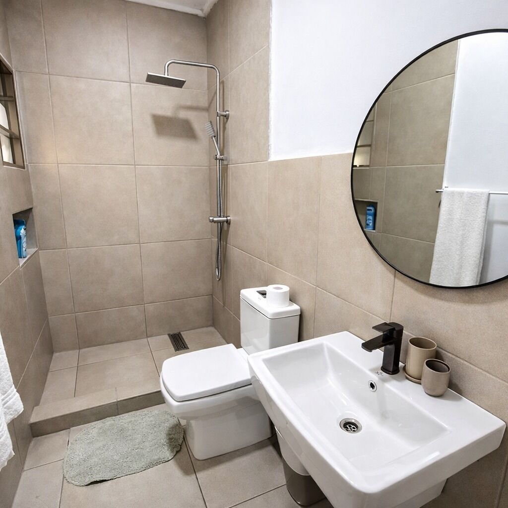 Une salle de bain moderne équipée d’une douche, de toilettes, d’un lavabo et d’un miroir rond.