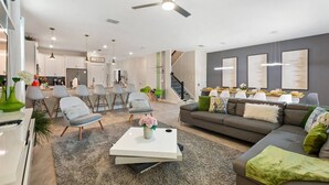 Ein modernes Wohnzimmer mit Sofa, Couchtisch und Sesseln. Eine Treppe führt zu einer weiteren Ebene.
