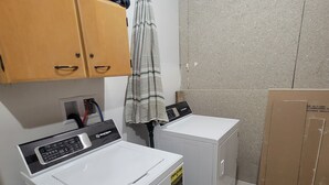 Un cuarto de lavandería con dos lavadoras, armarios de madera y un respiradero en el techo.