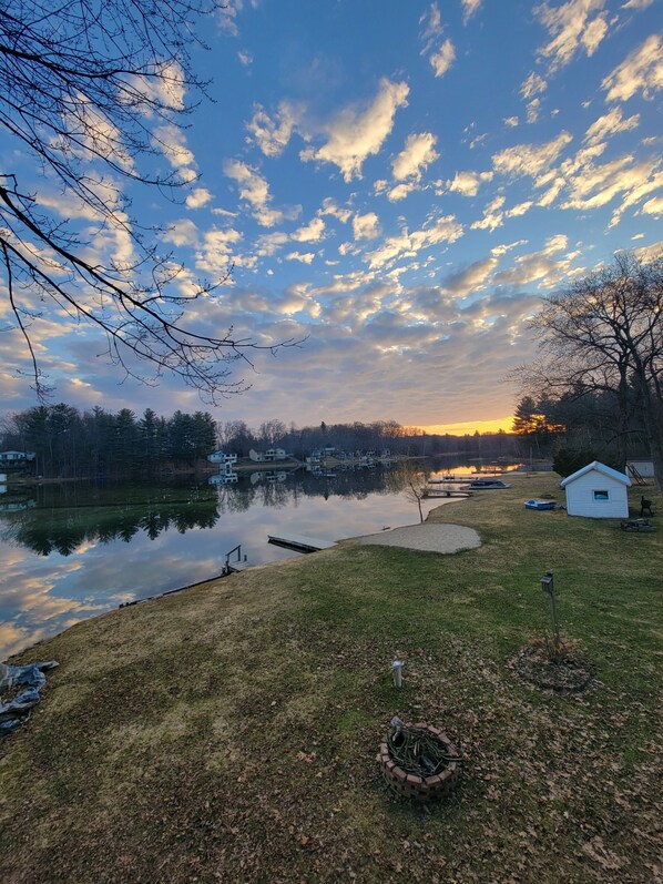 A lakeside property with a dock, a small shed, and a grassy area.