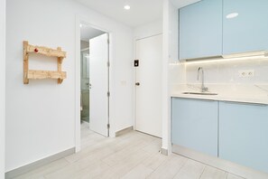 A modern kitchen with light blue cabinets, a white countertop, and a wooden wall-mounted rack. - Apartment 'Il Mare' with Sea View, Communal Pool and Wi-Fi (Almuñécar)