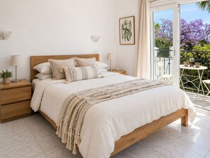 A bedroom with a wooden bed, bedside tables, a large window, and a balcony with plants. - Villa with private pool & casita + sea views (Mijas Costa)