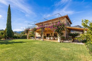 A stone house with a balcony, surrounded by a well-maintained lawn and a tall tree. - Charming Villa with Mountain Views, Wi-Fi & Air Conditioning in Selva (Selva)