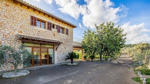 A stone building with a paved driveway, large windows, and a tree-lined path. - Charming Villa with Mountain Views, Wi-Fi & Air Conditioning in Selva (Selva)