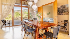 A dining area with a wooden table, wicker chairs, and a view of the outdoors. - Charming Villa with Mountain Views, Wi-Fi & Air Conditioning in Selva (Selva)