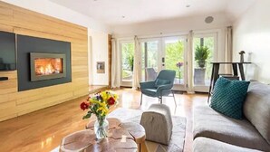 Un salon moderne avec une cheminée, un canapé, une table basse et un fauteuil.