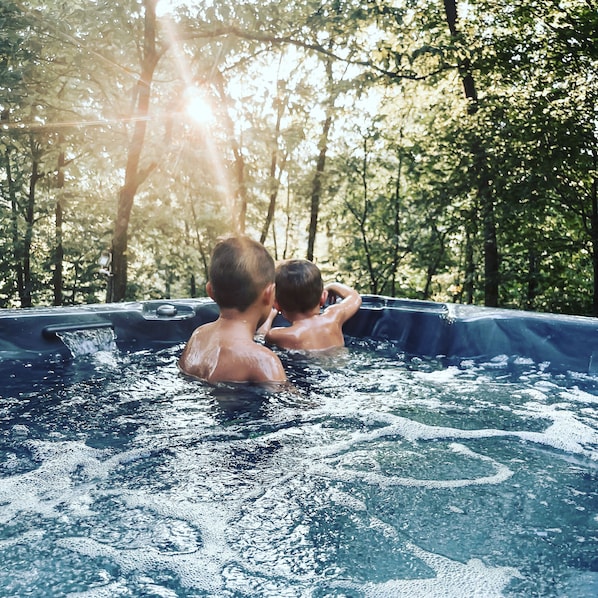 Two people in a hot tub surrounded by trees.