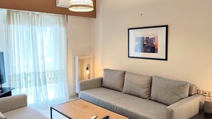 Un salon moderne avec un canapé, une table basse, un téléviseur et un tableau encadré au mur.