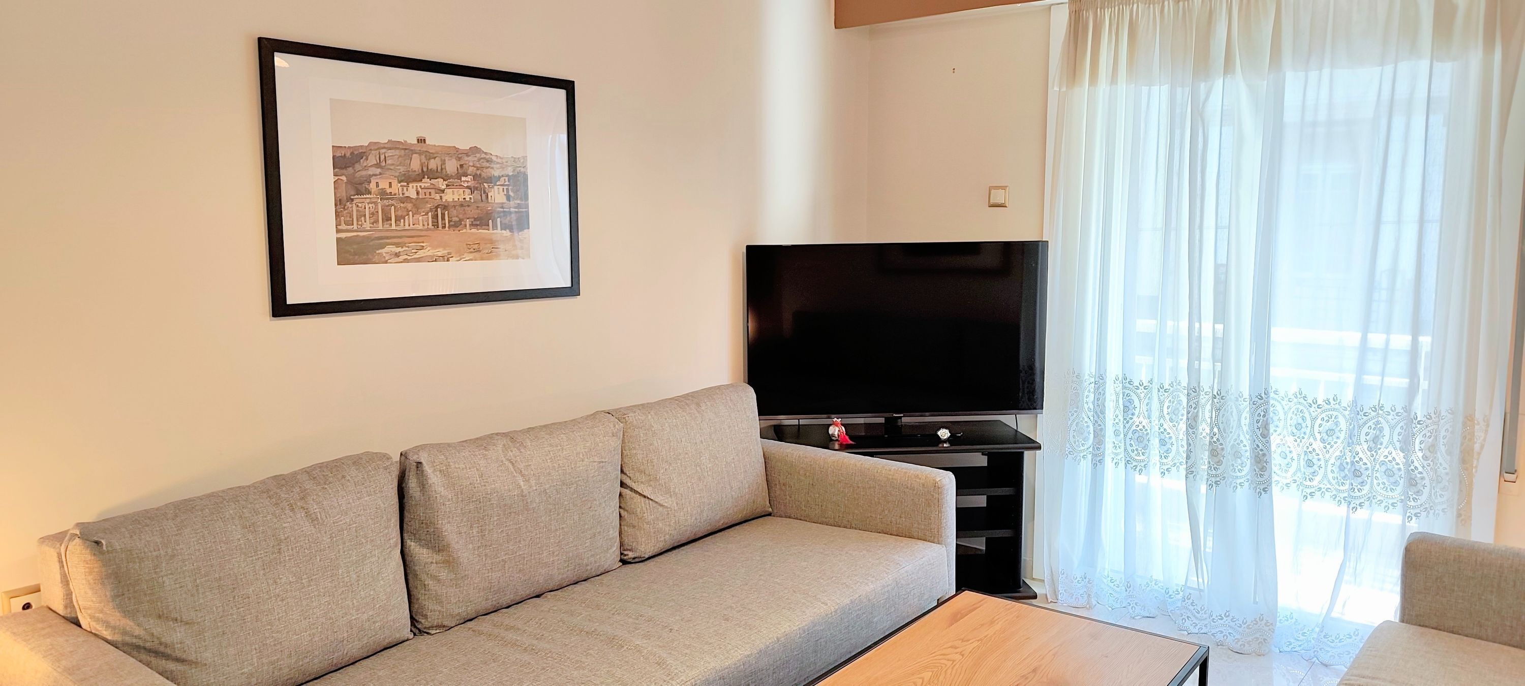 A living room with a sofa, a flat-screen TV, and a framed picture on the wall.