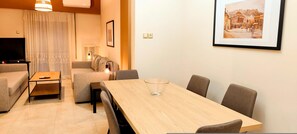 A modern living room with a sofa, a TV, a wooden dining table, and a framed picture on the wall. - Pretty apartment in Acropolis (Athens)