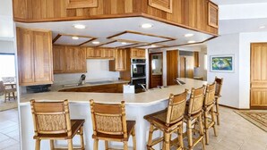 Een moderne keuken met houten kasten, een centraal eiland met barkrukken en geïntegreerde apparaten.