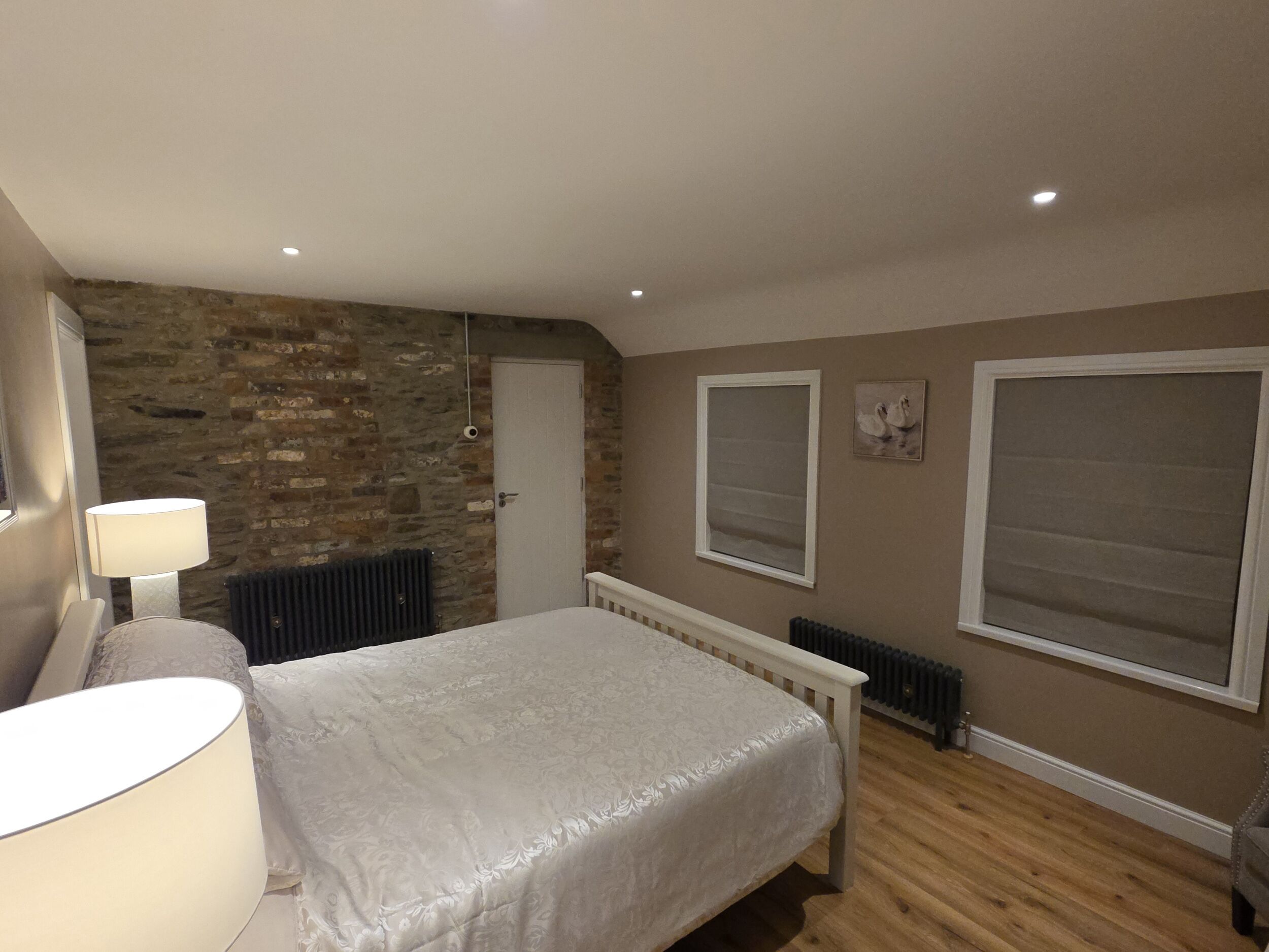 Een slaapkamer met een bed, een radiator, een deur en een raam met jaloezieën.