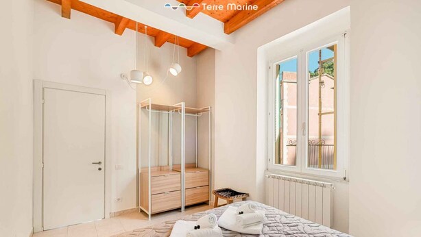 Une chambre à coucher comprenant un lit, une armoire, une fenêtre et un plafond avec des poutres en bois.