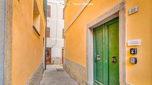 Une ruelle étroite avec un immeuble jaune, une porte verte et une enseigne portant le numéro « 22 ».