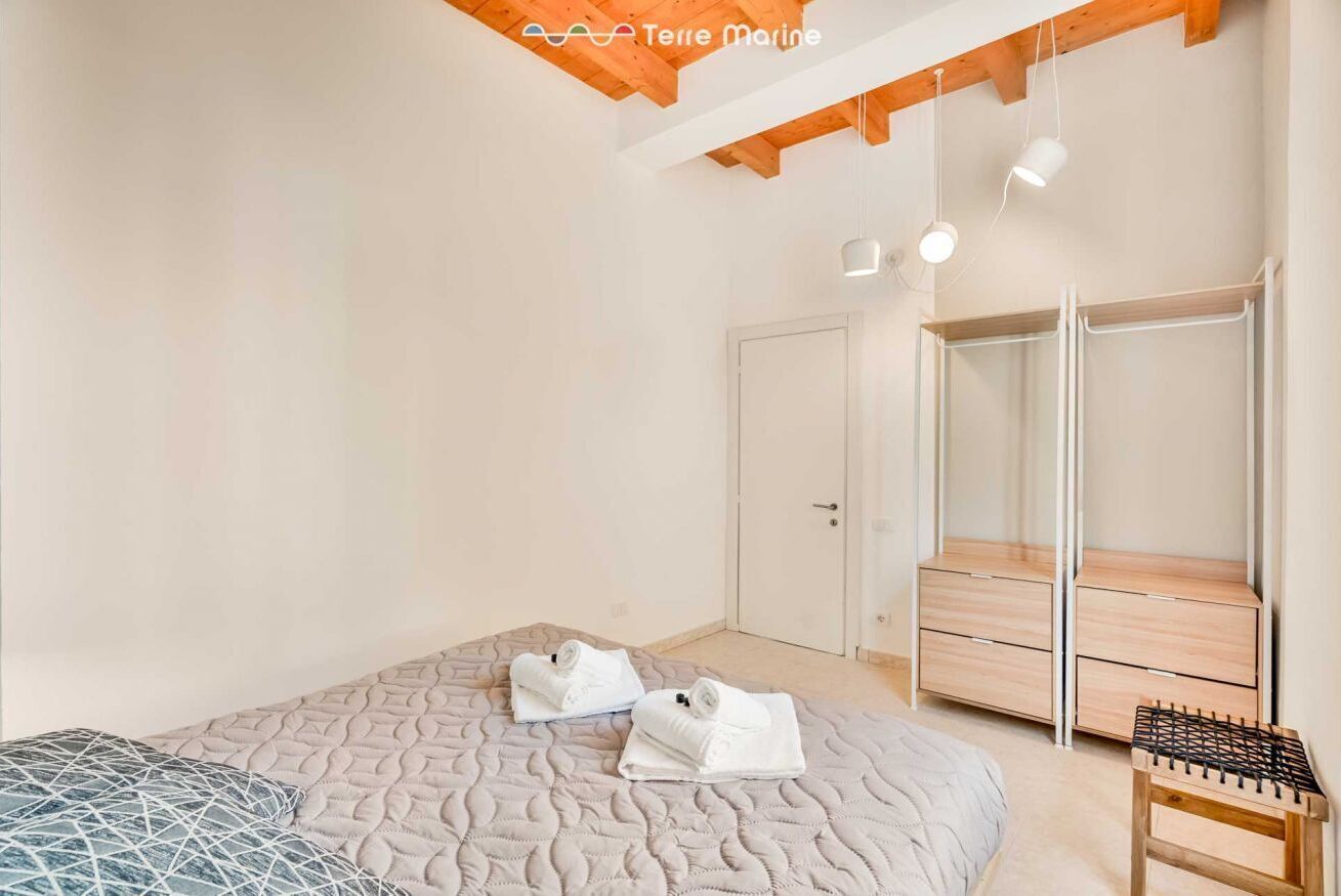 A bedroom with a bed, a wardrobe, and a small wooden stool.