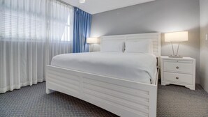 A hotel room with a white bed, two bedside tables with lamps, a ceiling fan, and a window with sheer curtains. - The Barbados | Private Balcony, Pool View! (Key West)