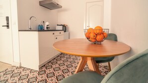 Uma cozinha compacta com pia, micro-ondas e uma tigela de laranjas sobre uma mesa pequena.