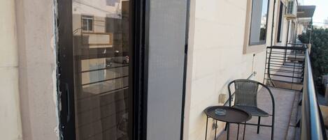 A balcony with a glass door, a small table, and two chairs.