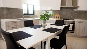 Une cuisine moderne avec un plan de travail blanc, des chaises noires et un îlot central.