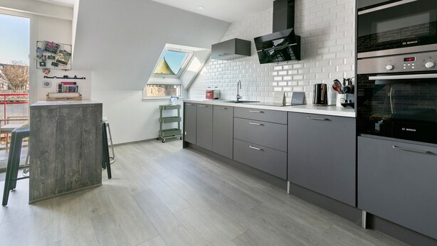 Una cocina moderna con armarios grises, un horno Bosch y una ventana con vistas al exterior.