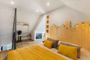 Une chambre à coucher avec un lit, une tête de lit en bois et un ventilateur.