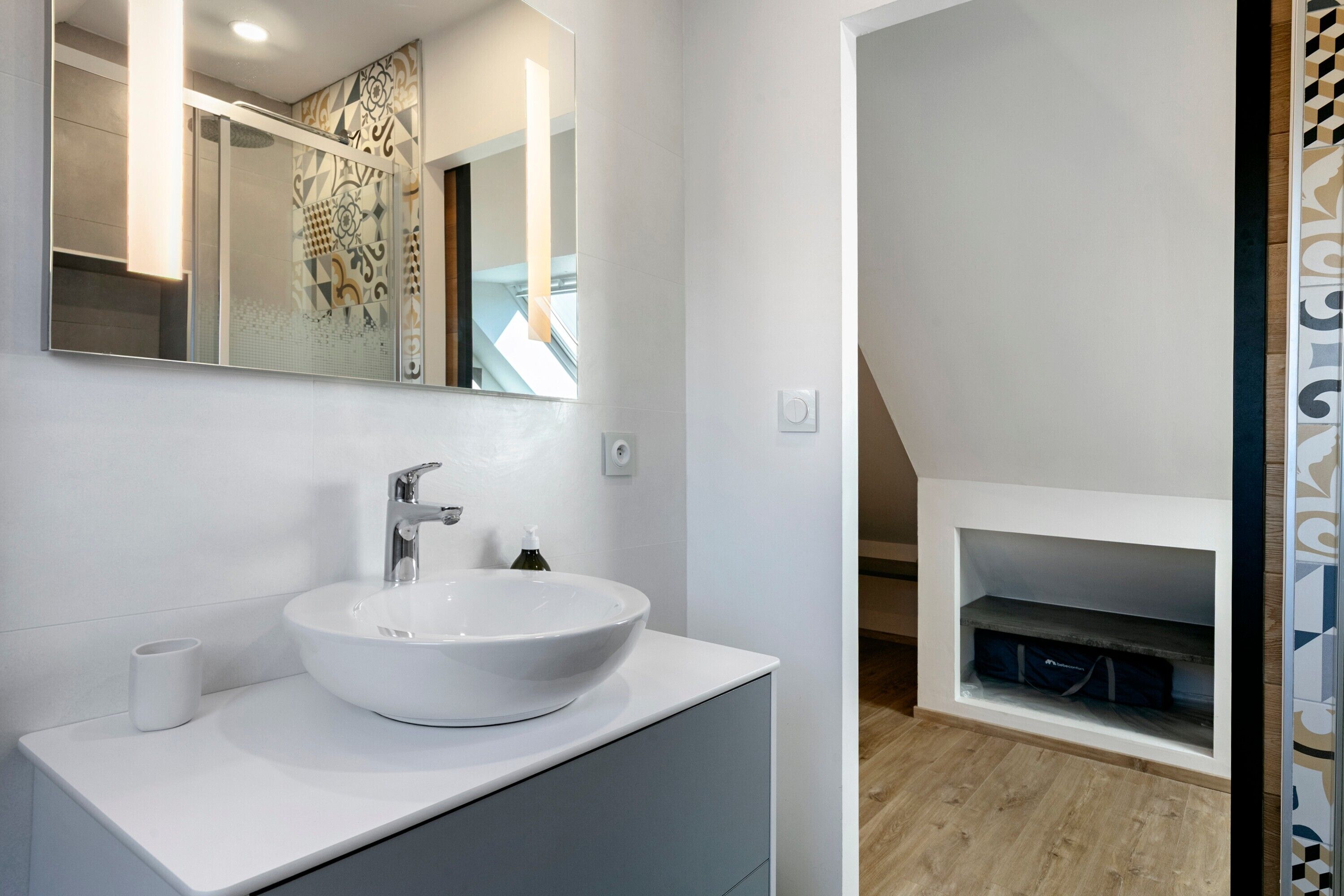 Une salle de bain moderne avec un grand lavabo blanc, un miroir et un espace douche.
