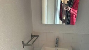 Une salle de bain avec un lavabo blanc, des meubles sombres et un porte-serviettes.