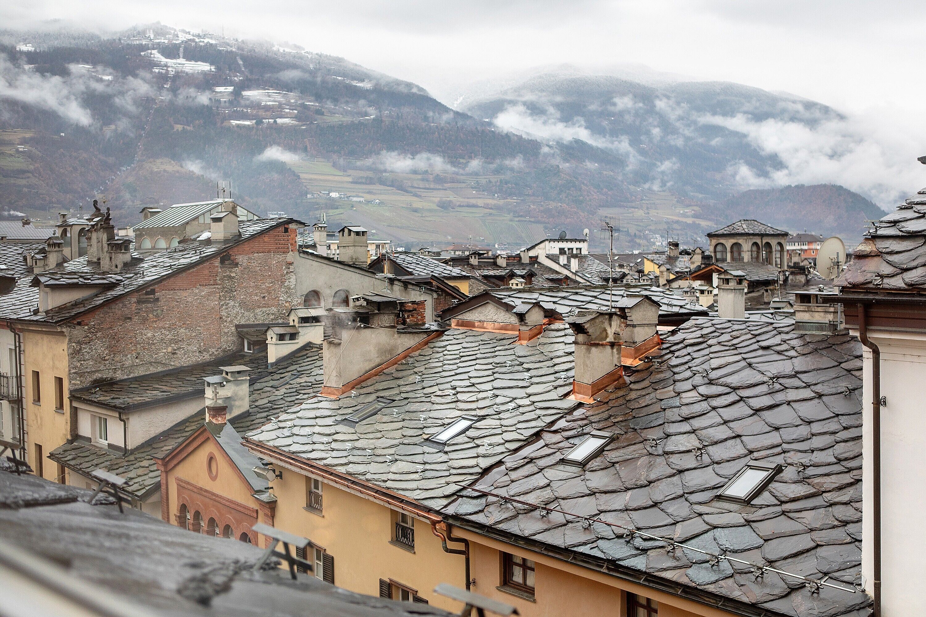 A mountainous town with traditional architecture, stone roofs, and a view of the valley.