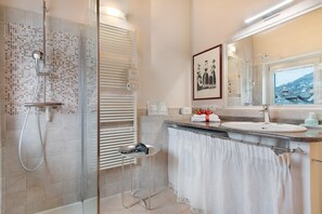A bathroom with a shower, a sink, a towel rack, and a window with a view. - Apartment 'Il Nido' with Mountain View, Wi-Fi and Air Conditioning (Aosta)