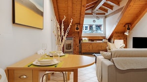 Un coin repas avec une table en bois mise pour le repas, une cuisine en arrière-plan et un salon confortable avec un canapé.