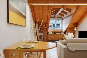 Un coin repas avec une table en bois mise pour le repas, une cuisine en arrière-plan et un salon confortable avec un canapé.
