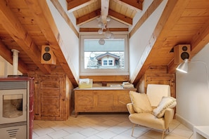 Een houten interieur met een keuken, een raam met uitzicht op een huis en een stoel.