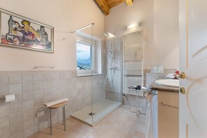 Une salle de bain moderne avec une douche à parois de verre, des toilettes, un lavabo et une fenêtre.