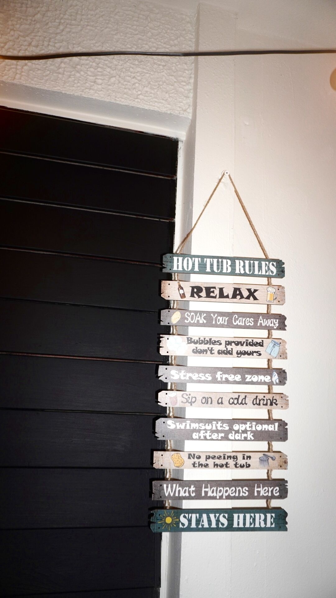 Un letrero de madera con la leyenda 'HOT TUB RULES' colgado en una puerta.