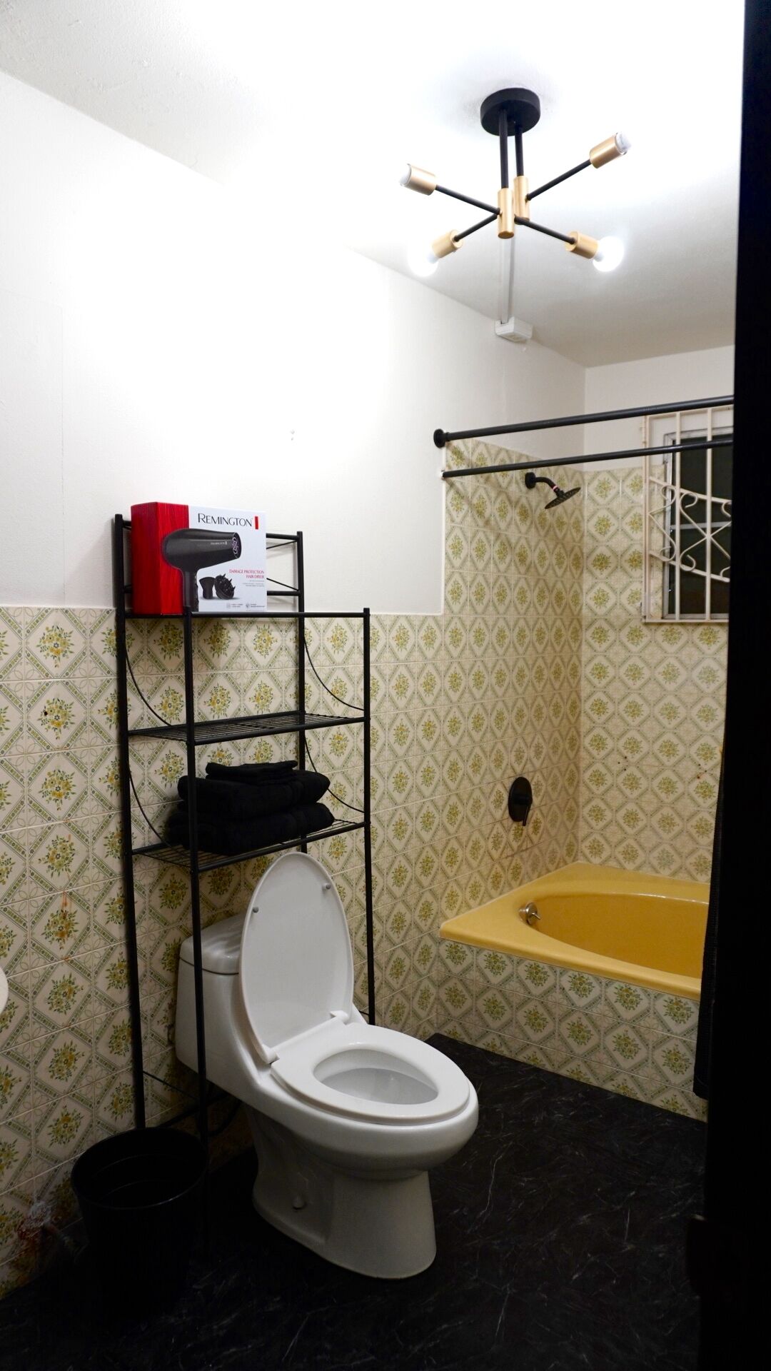 Ein Badezimmer mit Toilette, Ablagefläche mit einer roten Schachtel, Duschbereich und Badewanne.