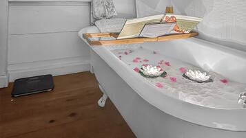 A bathroom with a bathtub, a towel, a book, and a small black object on the floor.