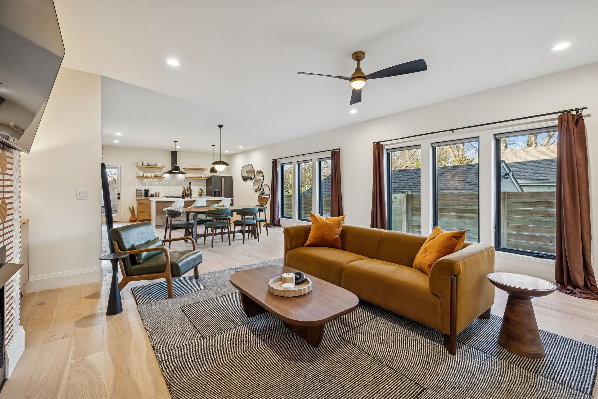 A spacious living room with a sofa, coffee table, and a dining area in the background.