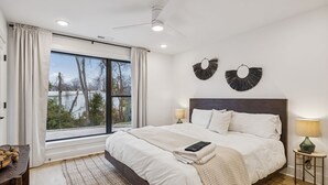 A bedroom with a large bed, a ceiling fan, a window with curtains, and two wall-mounted wall art pieces. - NEW Modern Nashville Escape with Rooftop Hot Tub (Nashville)