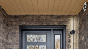 A dark-colored front door with a glass panel, a "HELLO" mat, and a mailbox on the right. - Luxury Nash Home w/ Rooftop Downtown Skyline Views (Nashville)