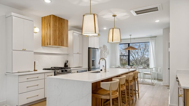 A modern kitchen with white cabinetry, a marble island, and pendant lighting. - Luxury Nash Home w/ Rooftop Downtown Skyline Views (Nashville)