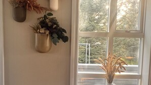 A room with a large window, a white wall, and three wall-mounted planters with dried plants. - Kot Guesthouse (Hvolsvöllur)
